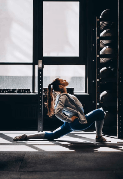Woman lunging on the floor beside a tall gym window