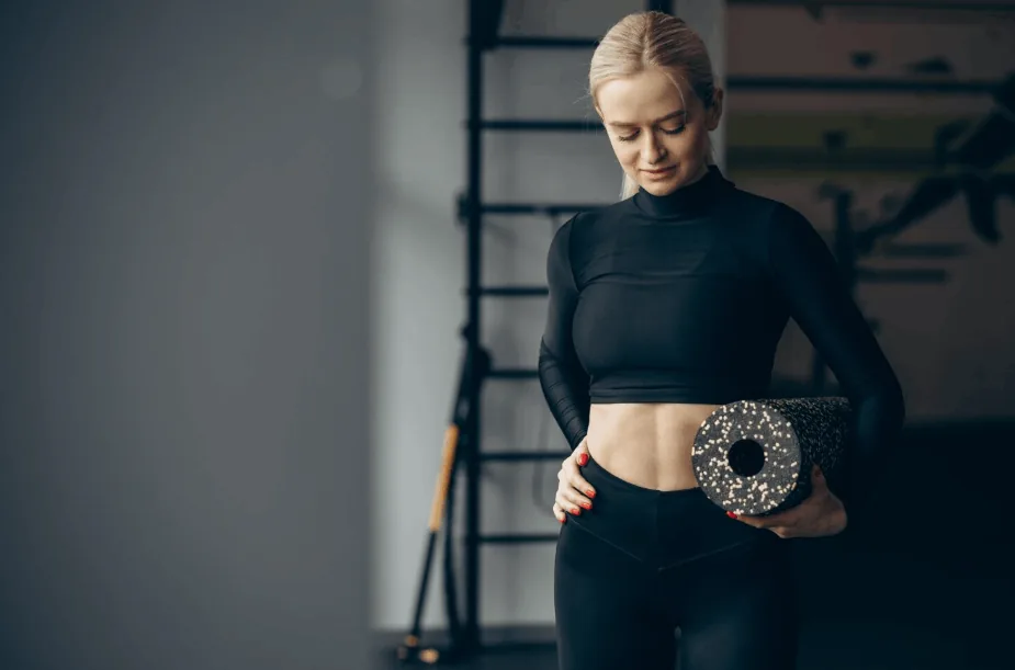 Woman in a black training set holding a foam roller