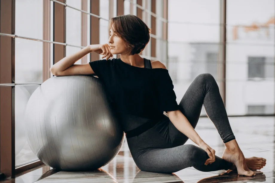 Woman sitting beside an exercise ball by a window