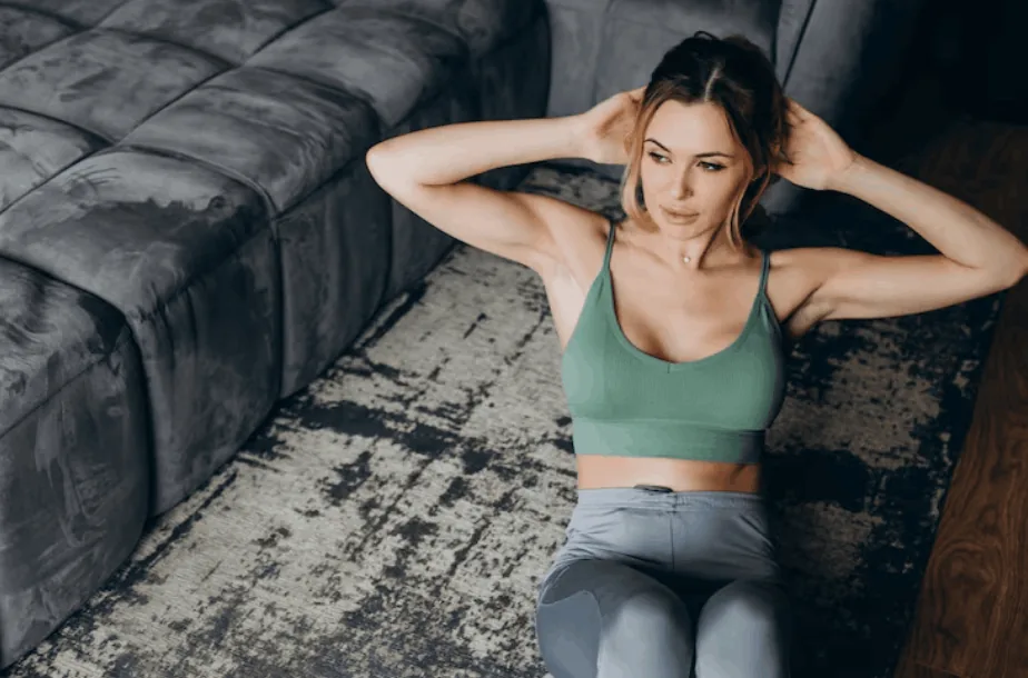 Woman doing sit-ups on a rug in a green sports bra